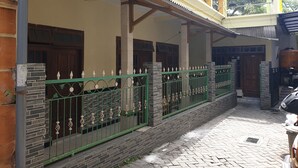 A two-story building with a covered porch, brick walls, and a green metal fence. - OYO Life  92620 Syfa Kost (Malang)