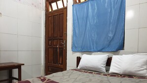 A bedroom with a bed, a wooden door, and a blue curtain. - OYO Life  92620 Syfa Kost (Malang)