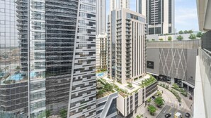A high-rise building with a modern architectural design, featuring a mix of glass and metal facades, and a rooftop garden. - Elegant Apartment Amidst Vibrant Area with Balcony (Dubai)