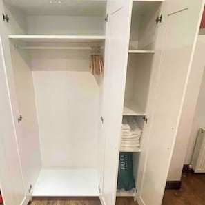 A white wardrobe with multiple shelves and hanging space. - Central  London | Walk to Soho, Oxford St & Shops (Greater London)
