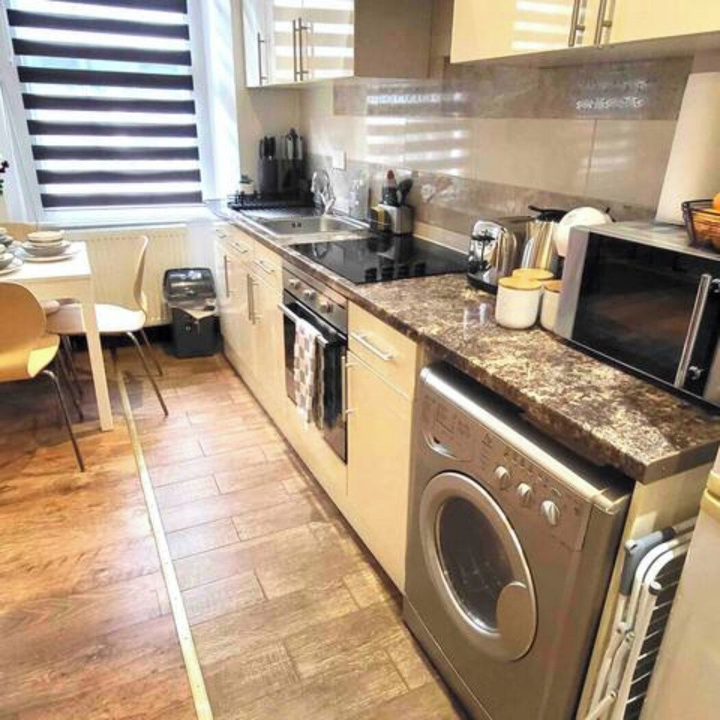Une cuisine compacte équipée d’un lave-linge, d’une cuisinière et d’un four à micro-ondes.