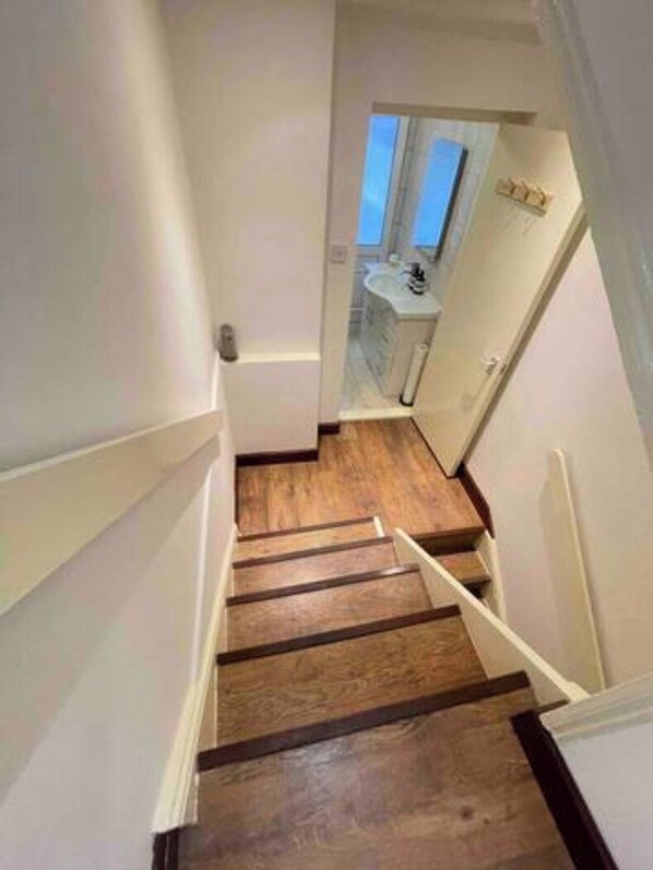 A narrow staircase with wooden steps leading to a bathroom with a sink and mirror. - Central London | Walk to Soho, Oxford St & Shops (Greater London)