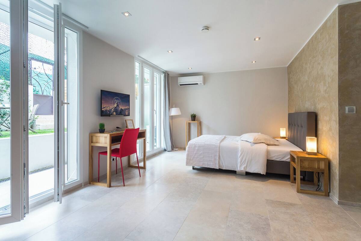Une chambre moderne avec un lit, une table de chevet et un bureau avec une chaise.