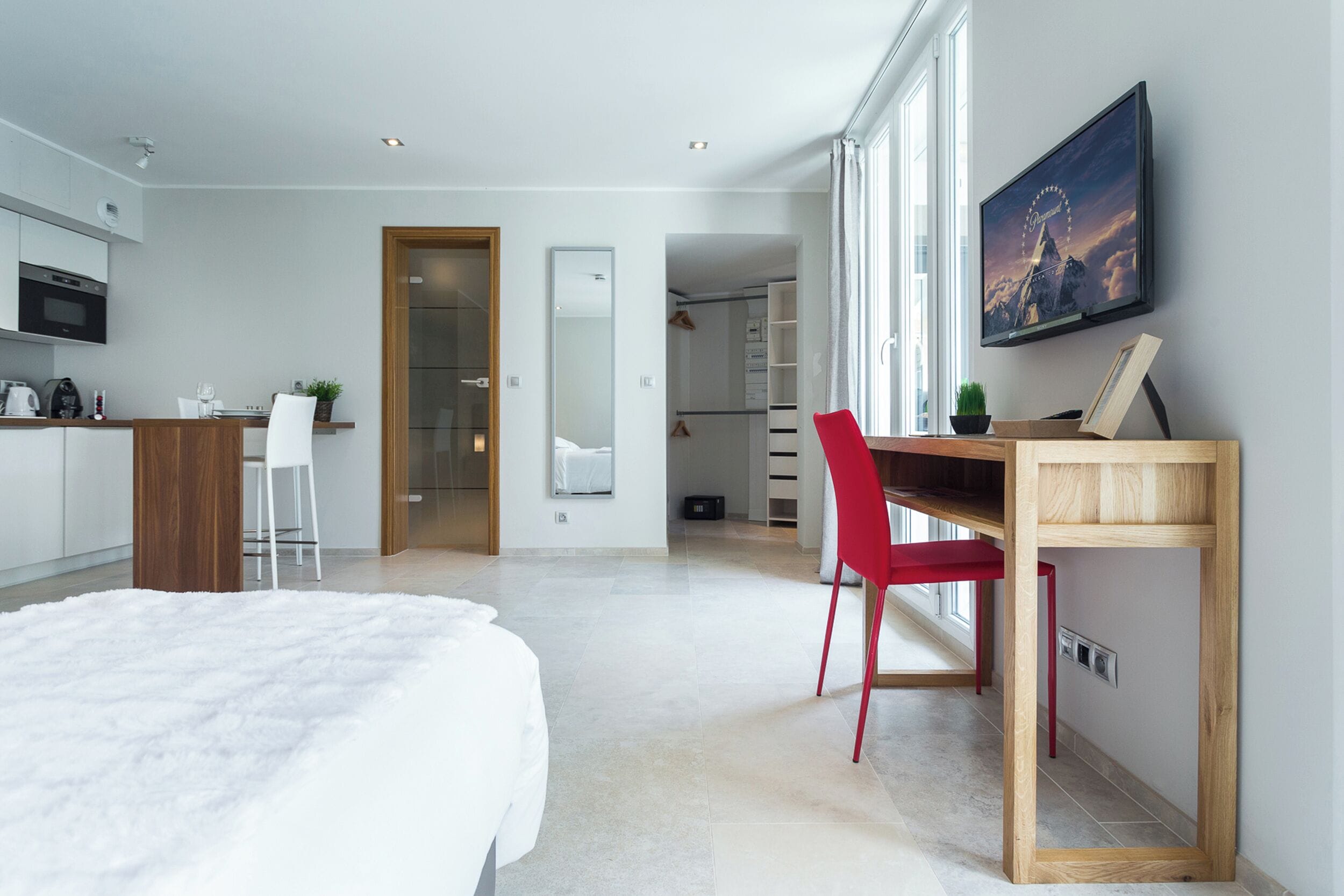 Una habitación de hotel moderna con una cama, un escritorio, una silla, un televisor y vistas a la Torre Eiffel.
