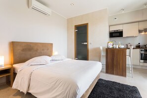 Ein modernes Hotelzimmer mit einem großen Bett, Nachttischen, einem Schreibtisch und einer Küchenzeile.