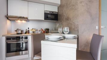 Una cocina moderna con electrodomésticos integrados, un comedor con una mesa dispuesta para dos personas y un amplio ventanal que proporciona luz natural.
