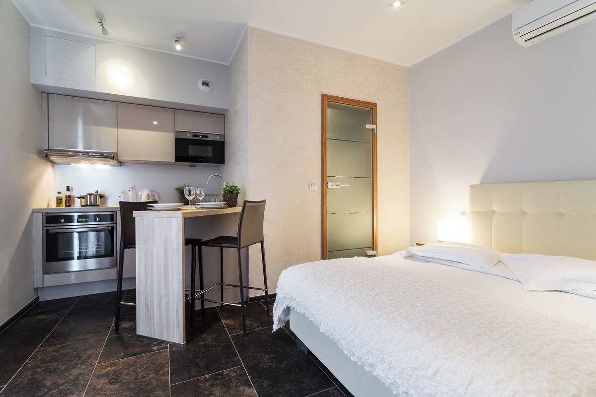 Une chambre d’hôtel compacte comprenant une kitchenette, un lit et une salle de bain.