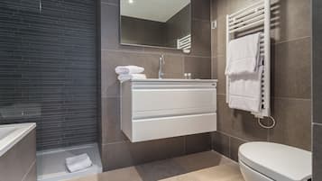 A modern bathroom with a bathtub, a sink with a mirror, and a toilet.
