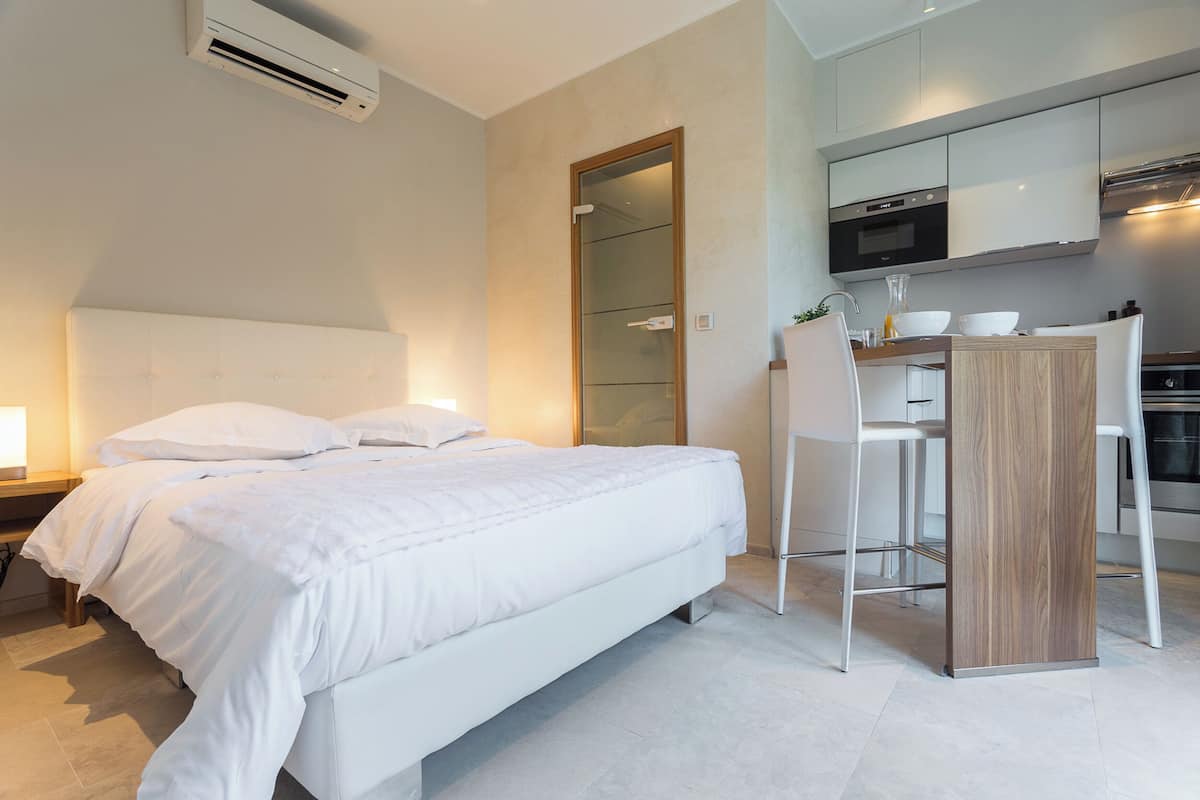 Une chambre d’hôtel moderne équipée d’un lit, d’une table de chevet et d’un coin cuisine.