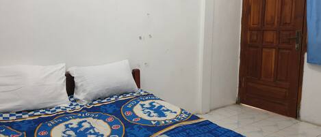 Un dormitorio con una cama, dos almohadas blancas y una colcha de diseño azul y blanco.