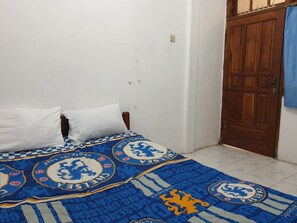 Une chambre à coucher avec un lit, deux oreillers blancs et une couvre-lit à motifs bleus et blancs.