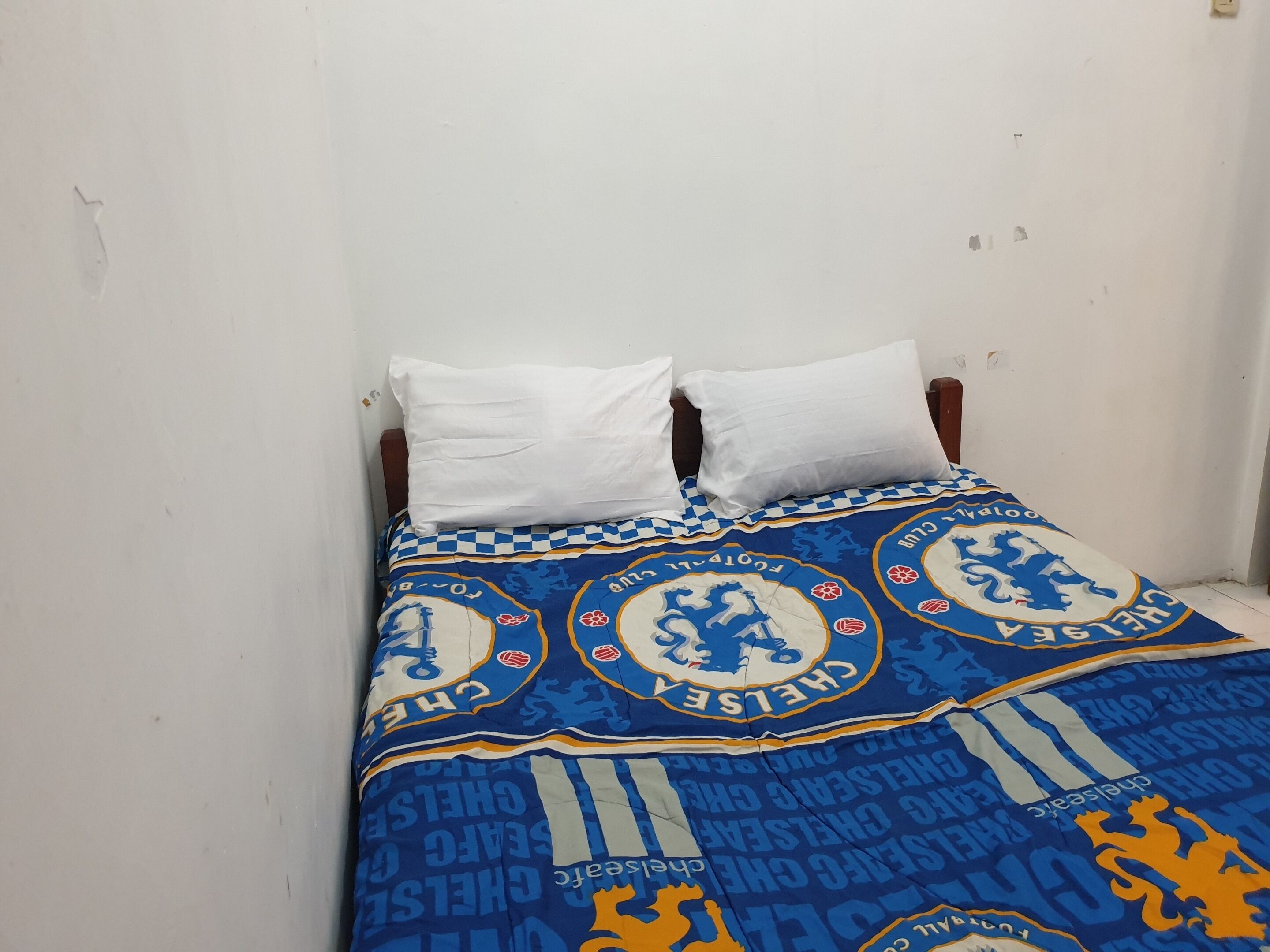 Una cama con una colcha azul y blanca estampada y dos almohadas blancas.