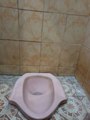 Des toilettes au design simple, avec des murs carrelés et un sol à motifs.