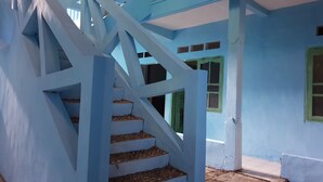 Una escalera azul con un diseño geométrico que lleva a un edificio con ventanas de marco verde.