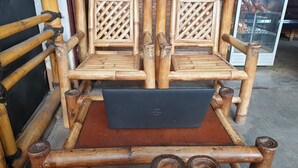 Una silla de bambú con una computadora portátil sobre una mesa de madera.