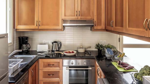 Una cocina con armarios de madera, un horno de acero inoxidable, una cafetera y varios electrodomésticos.