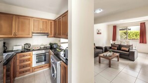 Una cocina moderna con armarios de madera, electrodomésticos de acero inoxidable y una zona de comedor con sofá y mesa de centro.