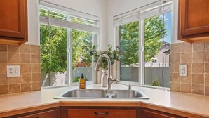 Una cocina con un lavamanos doble, armarios de madera y una ventana que da a zonas verdes.