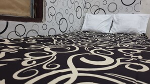 A bed with a black and white patterned bedspread, white pillows, and a wall with circular patterns. - OYO Life 92622 Jatiluhur Kost Syariah (Malang)