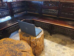 A traditional wooden furniture setting with a laptop on a carved wooden stool.