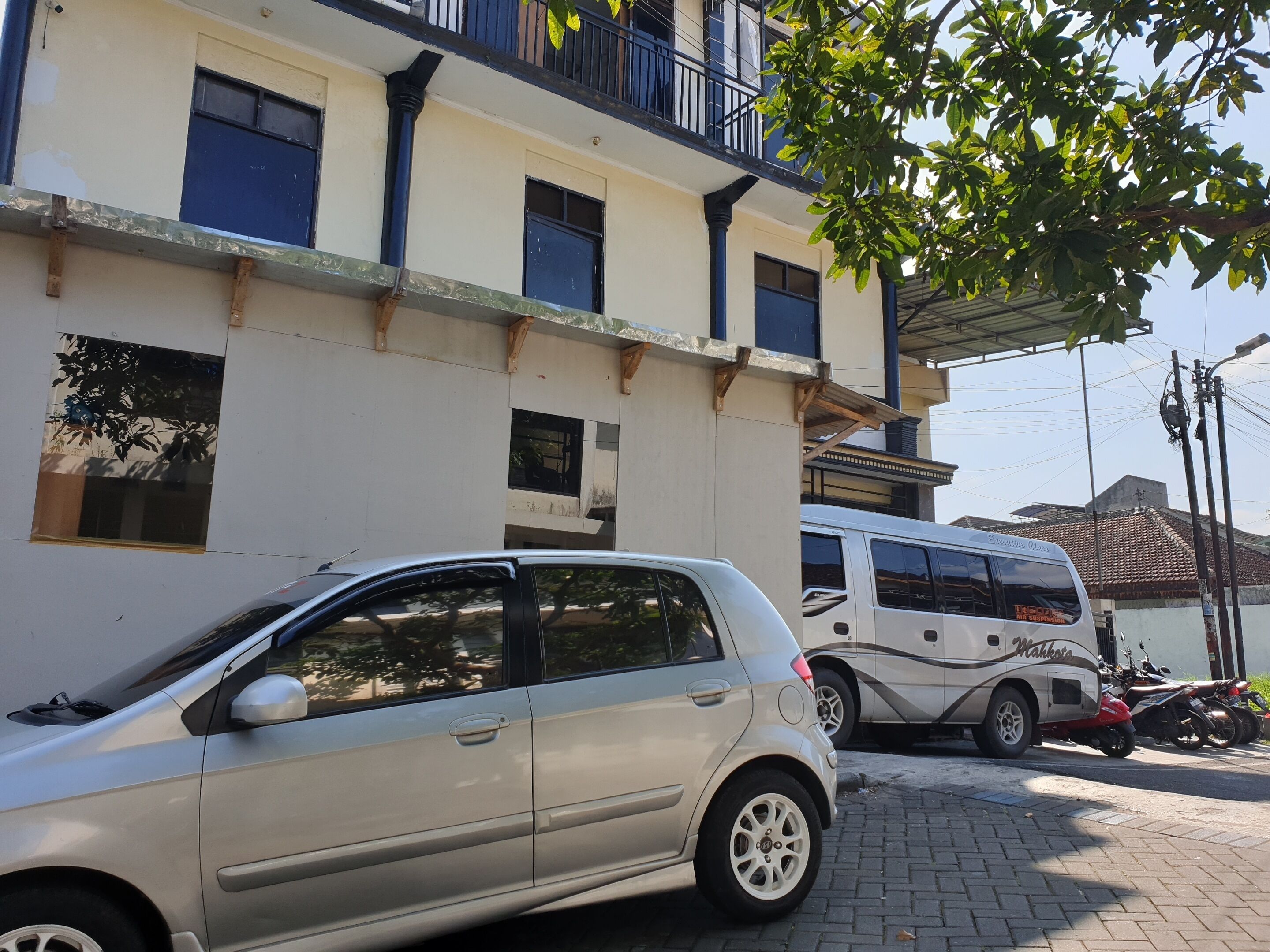 A building with multiple windows and balconies, a parked car, and a white van.