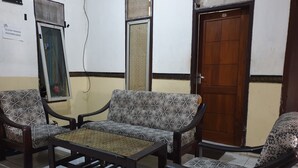 A room with two patterned sofas, a wooden coffee table, and a wooden door. - OYO Life 92622 Jatiluhur Kost Syariah (Malang)