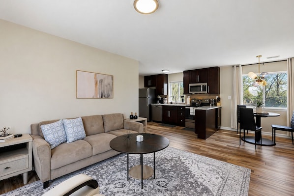 A modern living room with a sofa, coffee table, and a dining area with chairs.