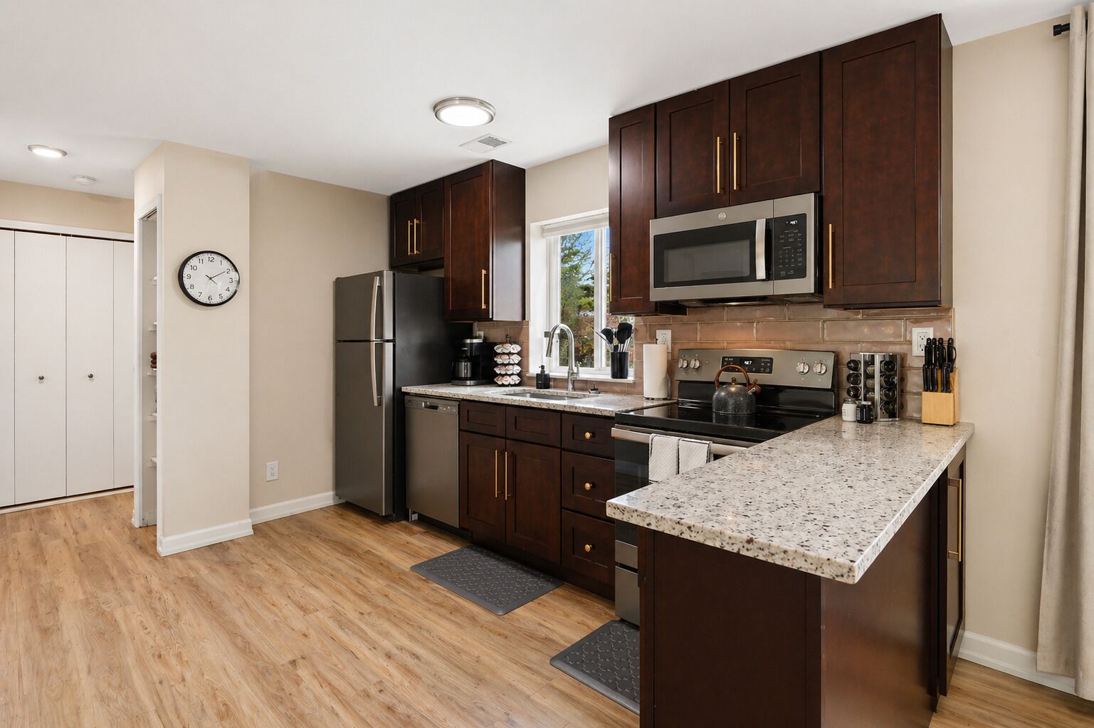A modern kitchen with dark wood cabinets, stainless steel appliances, and a granite countertop.
