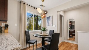 Una cocina moderna con encimera de granito, sillas negras y una mesa de comedor redonda.