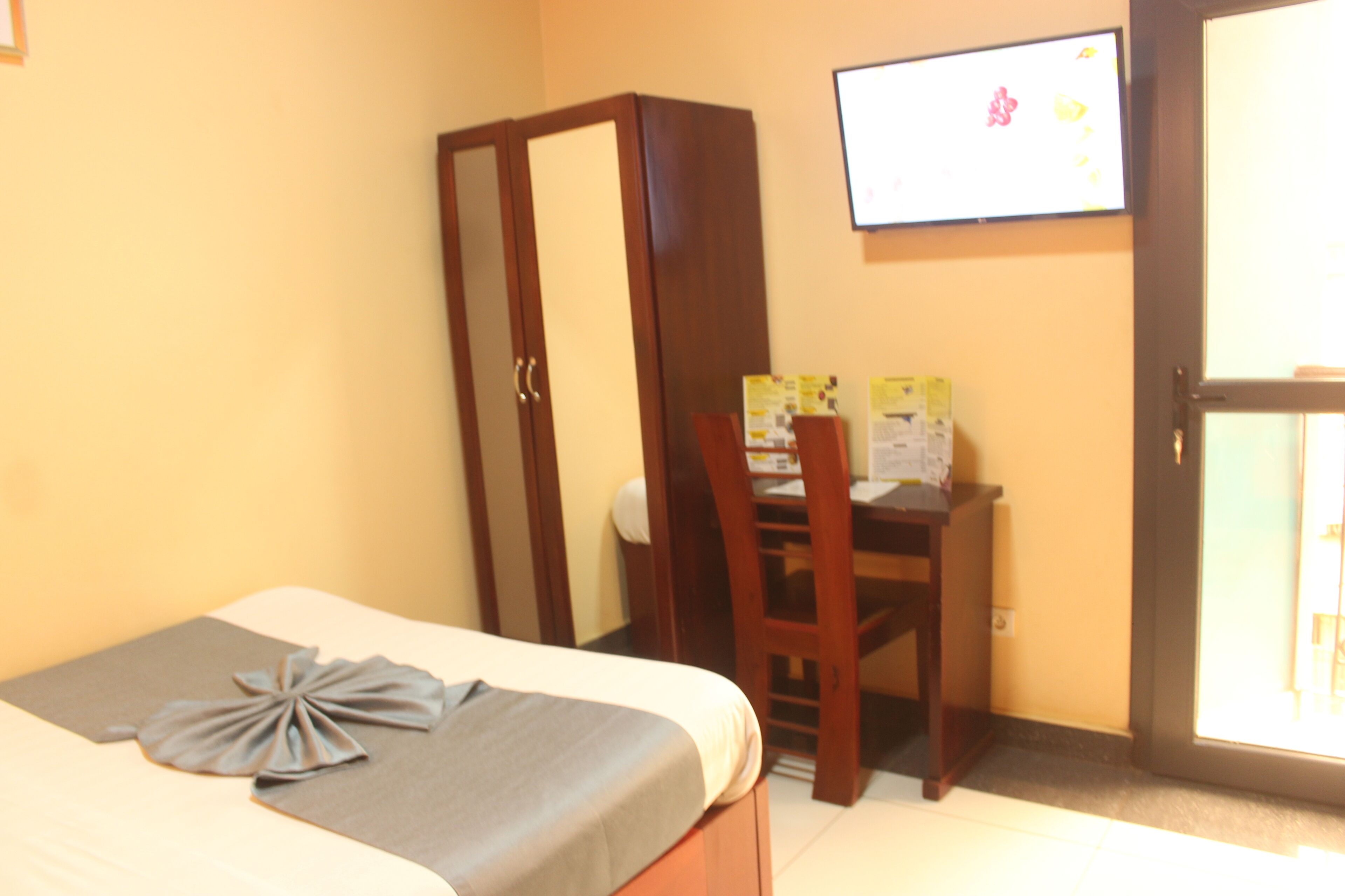 A hotel room with a bed, a desk, and a wardrobe.