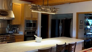 Una cucina moderna con soffitto in legno, elettrodomestici in acciaio inossidabile e un'isola centrale con posti a sedere.