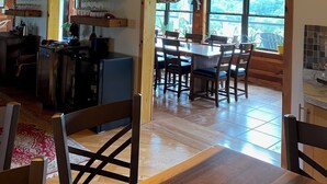 Un'ampia cucina con mobili in legno, un'area pranzo con un tavolo e sedie di grandi dimensioni, e vista attraverso una finestra.
