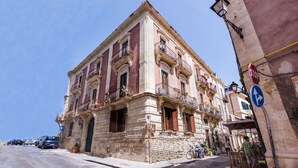A historic building with multiple balconies, a street in front, and a clear blue sky.