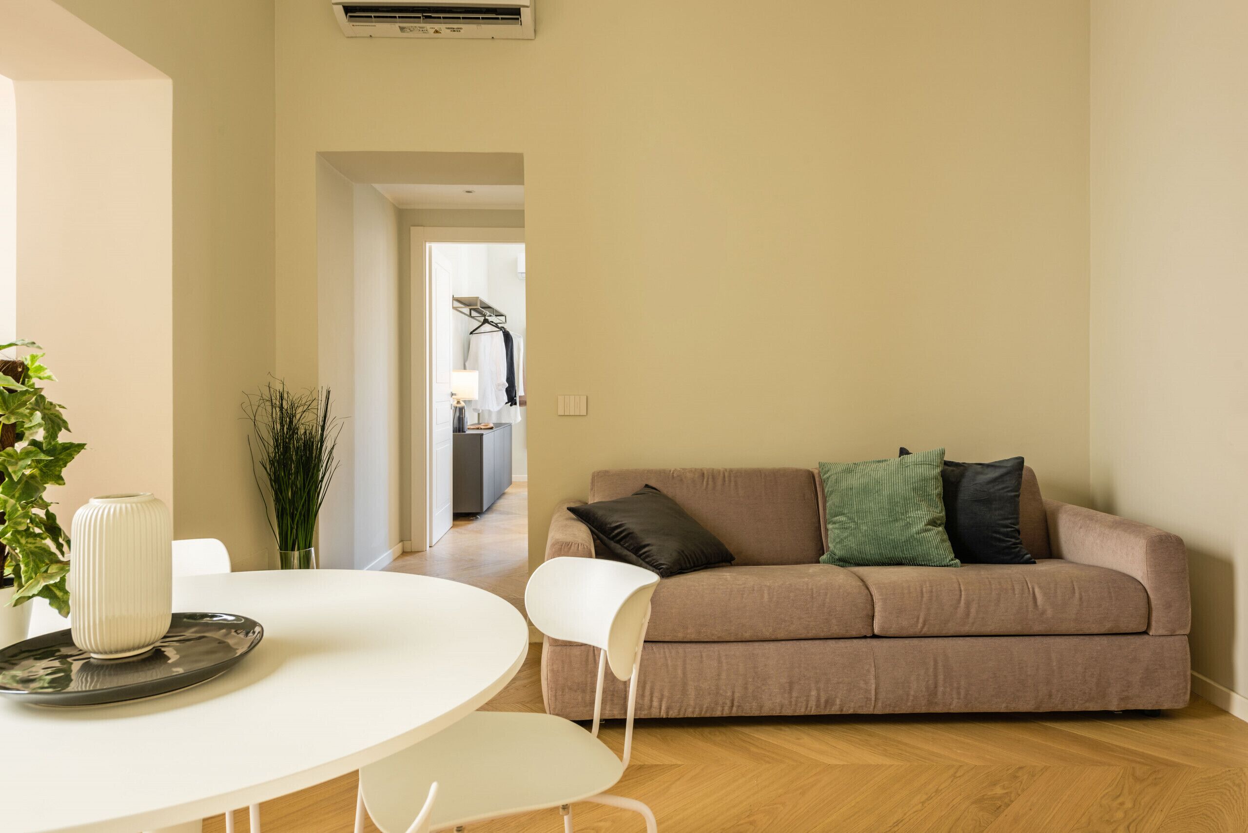 A living room with a beige sofa, a white table, and a potted plant.