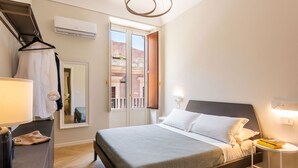 Een slaapkamer met een bed, nachtkastje, lamp en uitzicht.