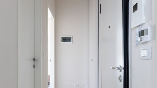 A narrow hallway with wooden flooring, white walls, and a black-framed door on the right. - Crociali Apartment by Wonderful Italy (Bologna)