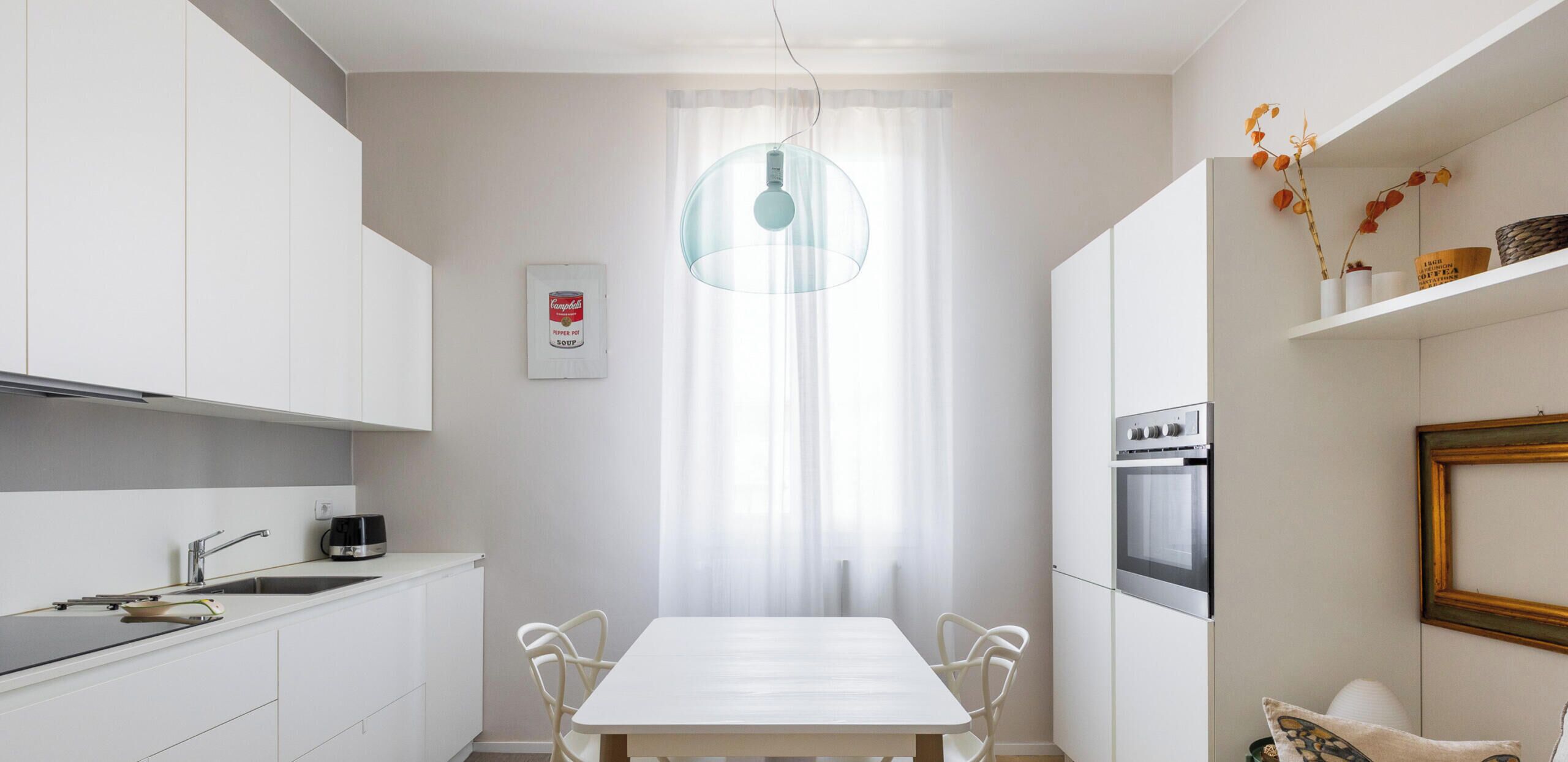 Une cuisine moderne avec des meubles blancs, une table à manger et un canapé.