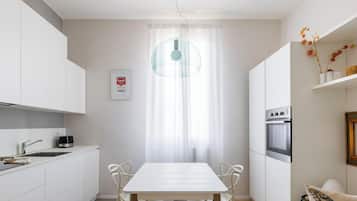 Une cuisine moderne avec des meubles blancs, une table à manger et un canapé.