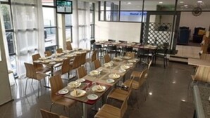 A dining area with multiple tables and chairs, a television screen, and a sign indicating a medical center. - Hostel Funchal XII (Funchal)