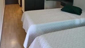 A bedroom with two beds, a dark wardrobe, and a light-colored floor. - Hostel Funchal XII (Funchal)