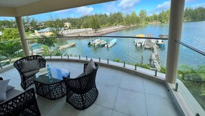 A balcony with outdoor seating and a view of a lake with boats. - Mae Water Front Apartments (Mahé Island)