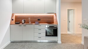 Une cuisine moderne avec des armoires blanches, un plan de travail en bois et un four encastré.