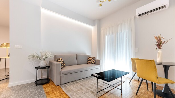 Un salon moderne avec un canapé gris, une table basse noire et un fauteuil jaune.