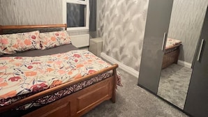 Een slaapkamer met een houten bed, een kledingkast en een raam.