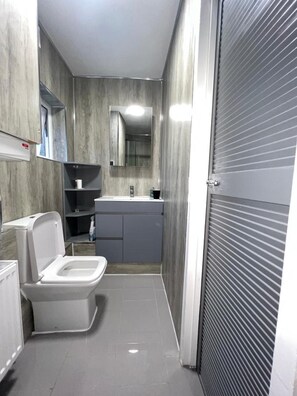 A modern bathroom with a toilet, sink, and mirror. - Lovely 2-bedroom Flat in London Stratford (London)