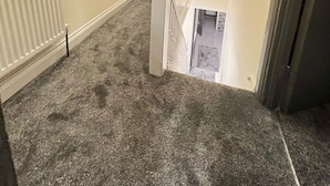Een betegelde trap met een witte leuning, een radiator aan de linkerkant, en een deur onderaan.