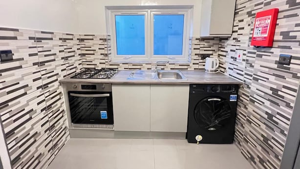 Een kleine keuken met een gasfornuis, dubbele spoelbak en een inbouwoven.