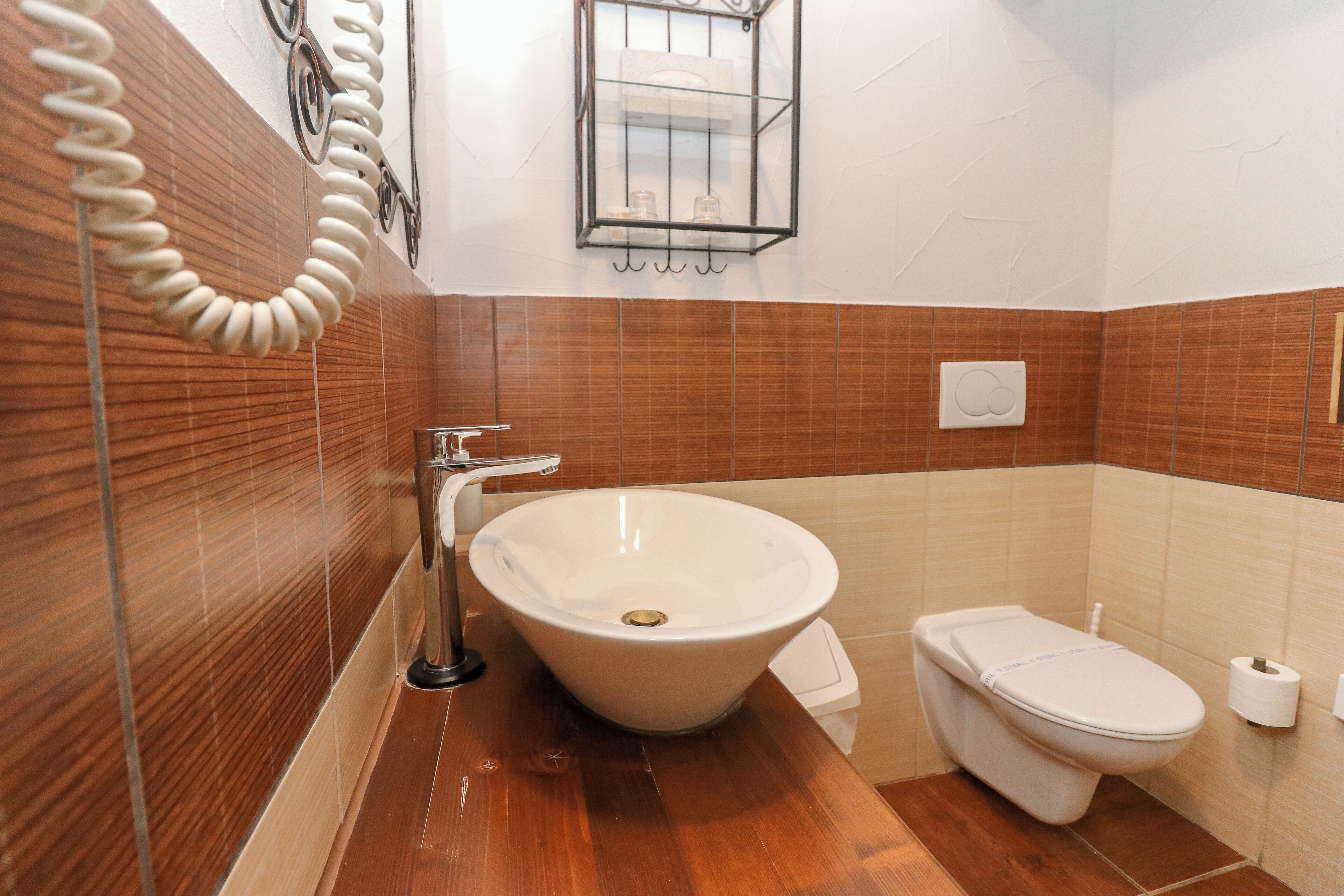 Une salle de bain avec un meuble-lavabo en bois, un lavabo blanc, des toilettes et un porte-serviettes.