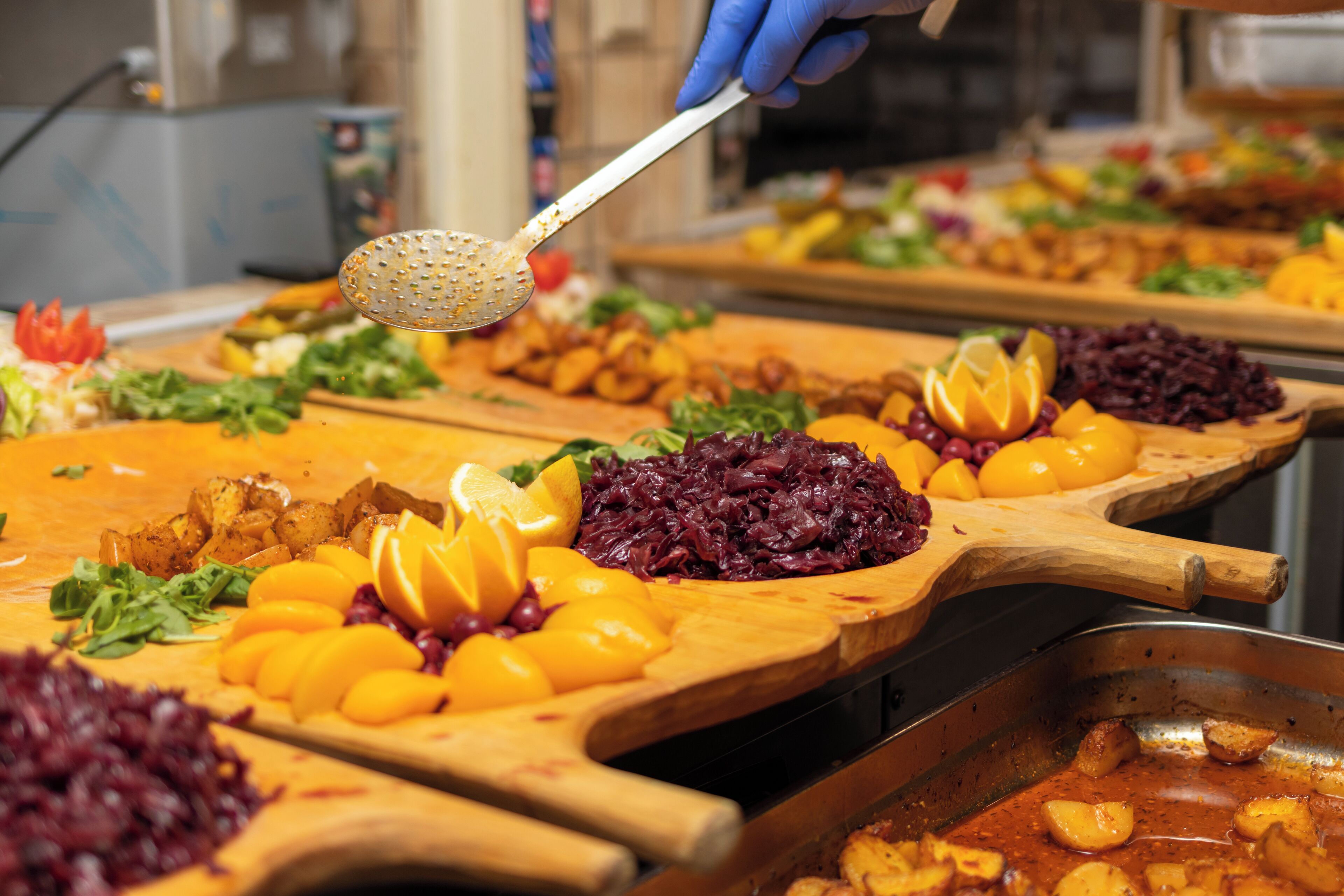 A buffet with various dishes including salads, fruits, and meats.