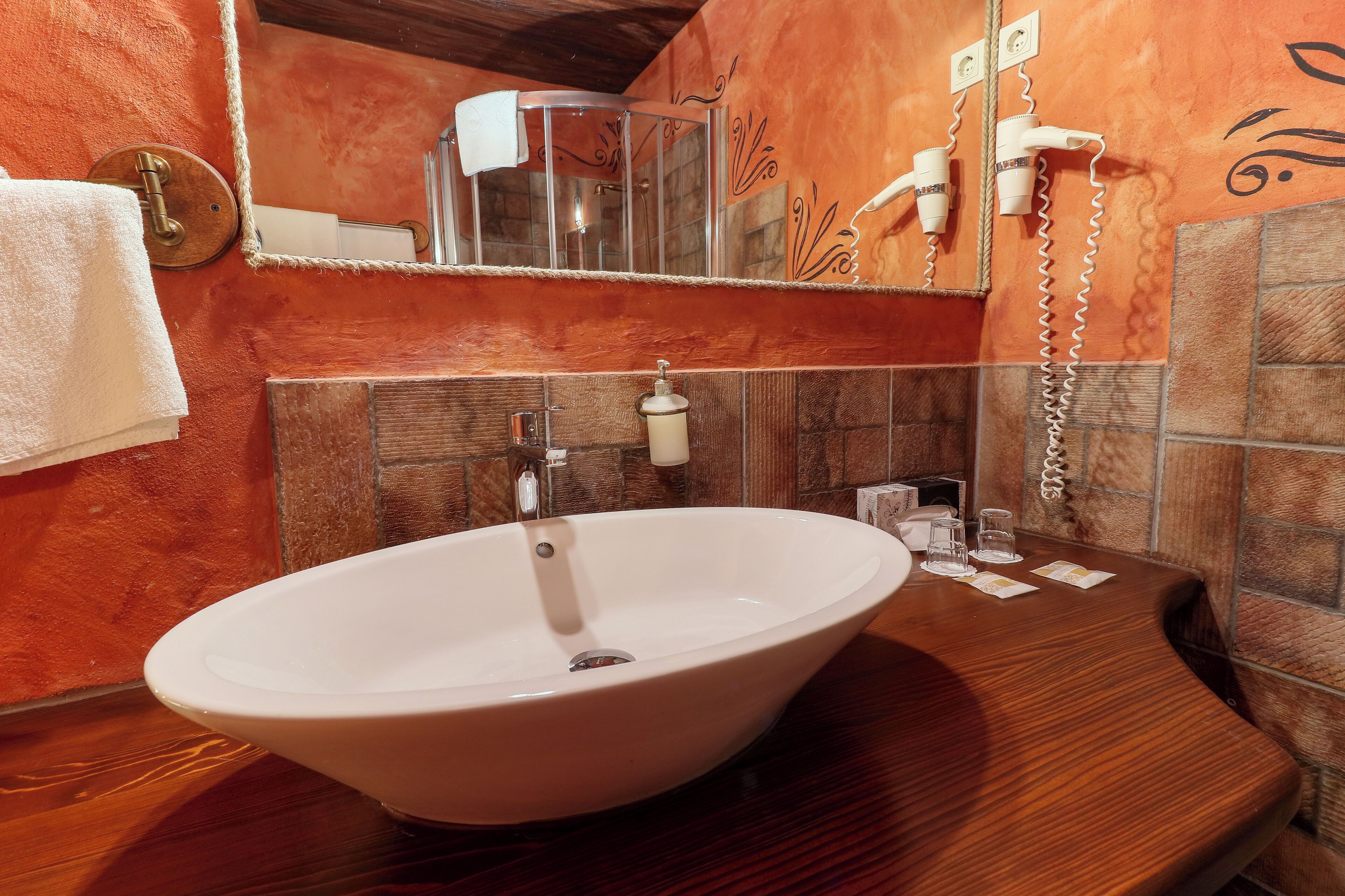 A bathroom with a large oval sink, a mirror, a towel rack, and a hairdryer.